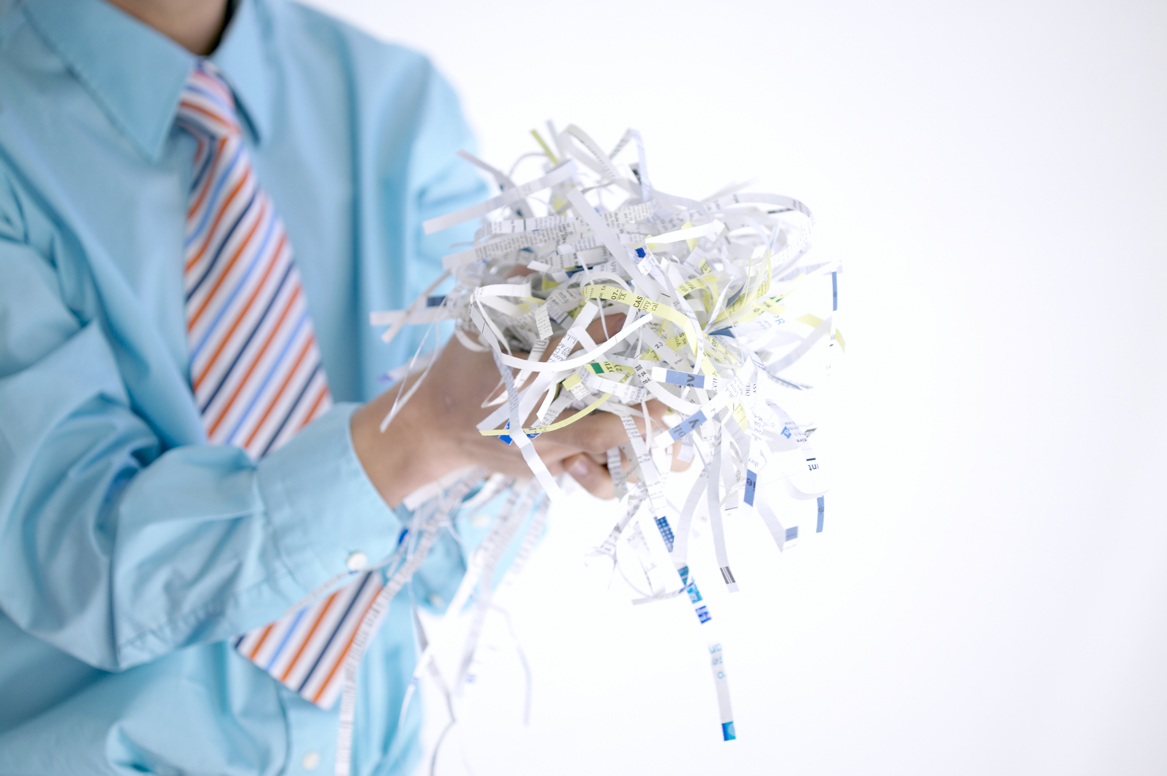 Man in business shirt holding shredded paper.